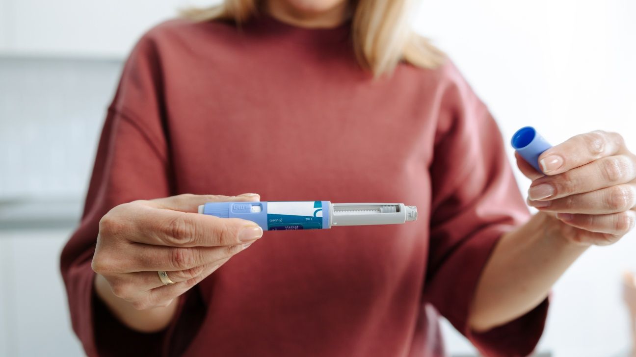 Female holding a GLP-1 injection pen in front of her