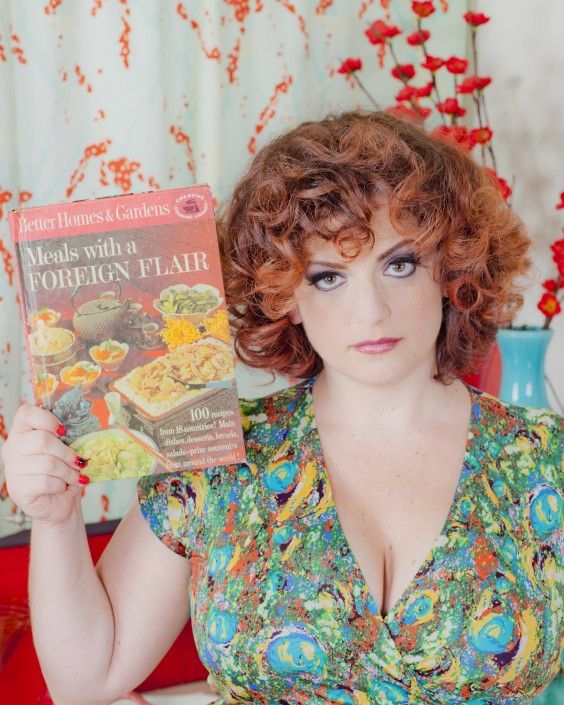 Sara, the author, looking very glam and posing with a cookbook - Photo courtesy of Iconic Pinups