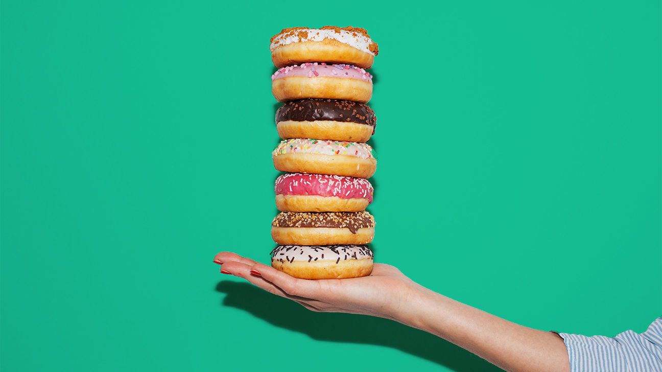 Hand holding a stack of donuts against a teal background