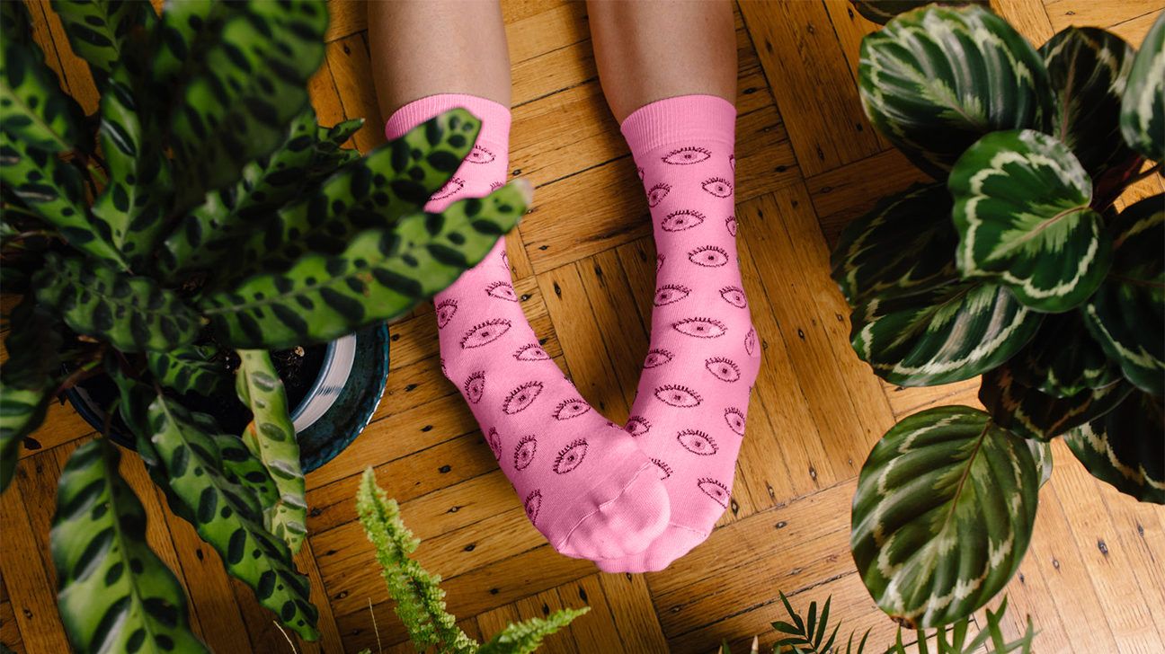 pink socks with eye print surrounded by plants
