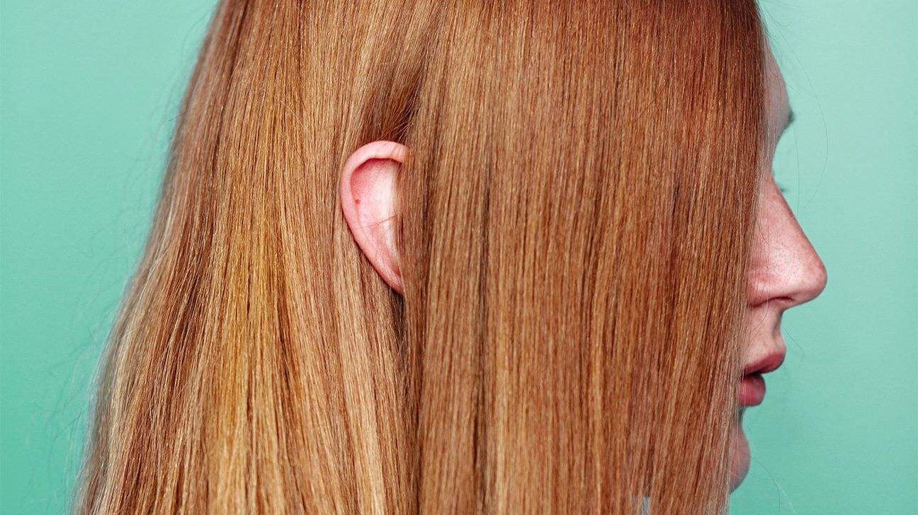 Profile view of red headed girl with her ear peeking through her hair. 
