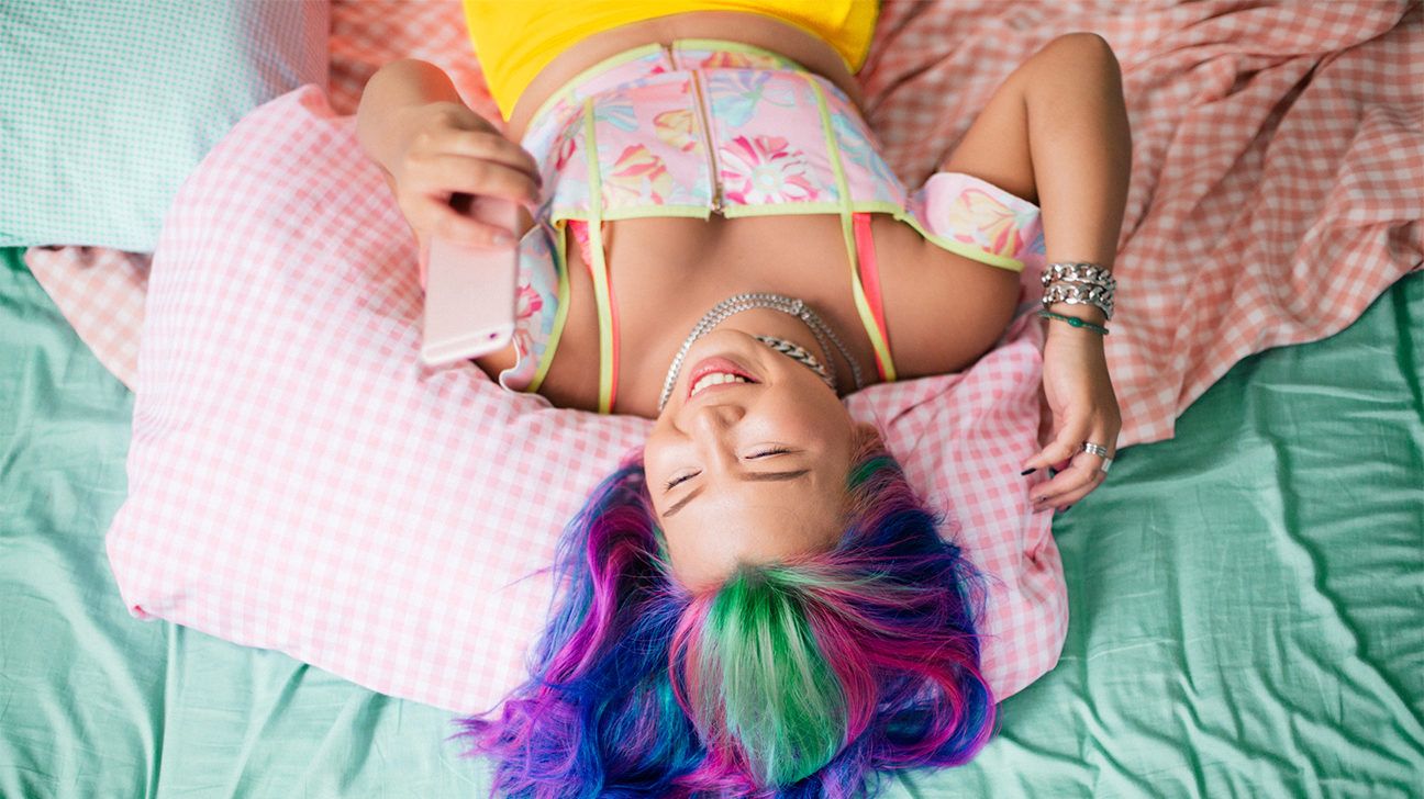 young woman using phone in bed