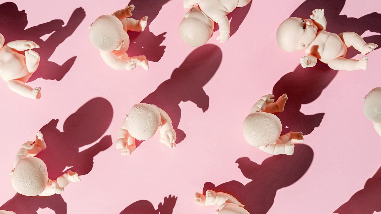 plastic baby dolls on a pink backdrop