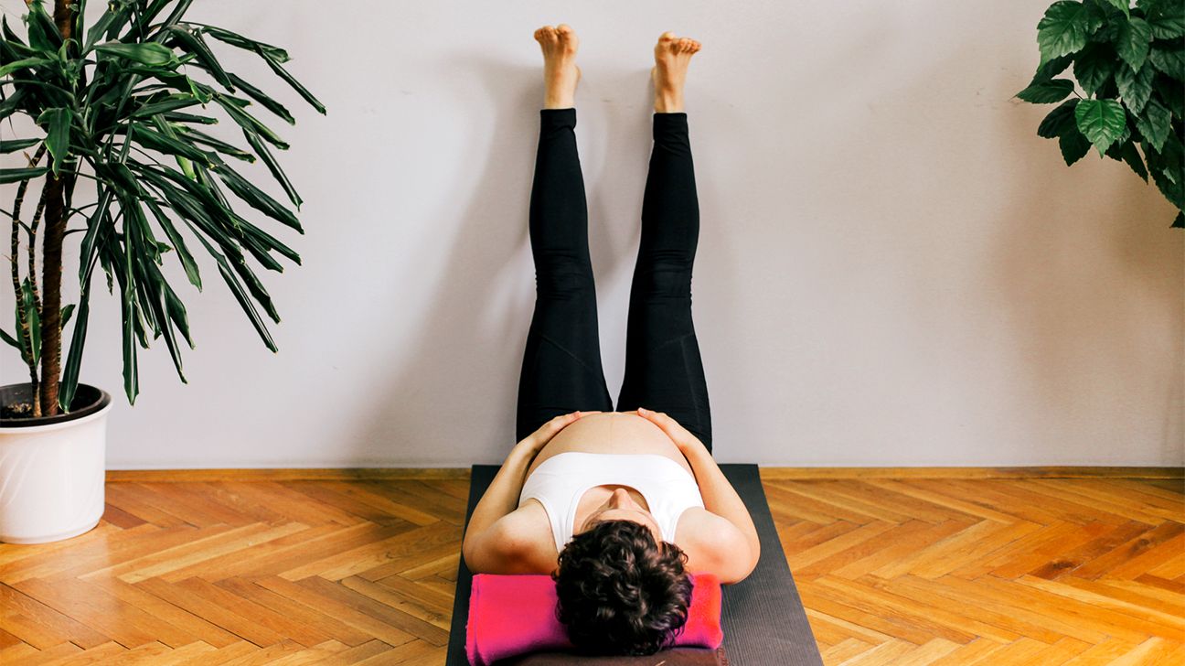 pregnant woman doing legs up against wall pose