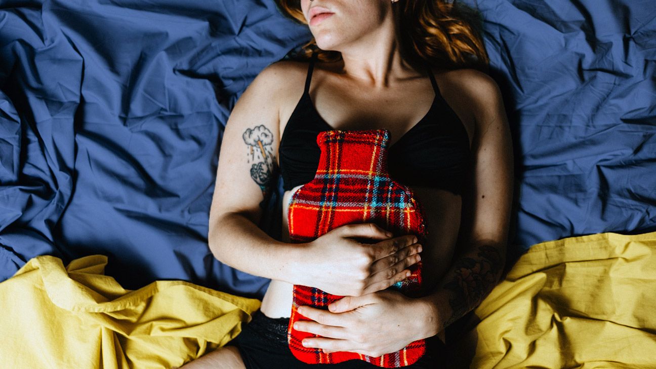 young woman in bed with a heating pad on her stomach