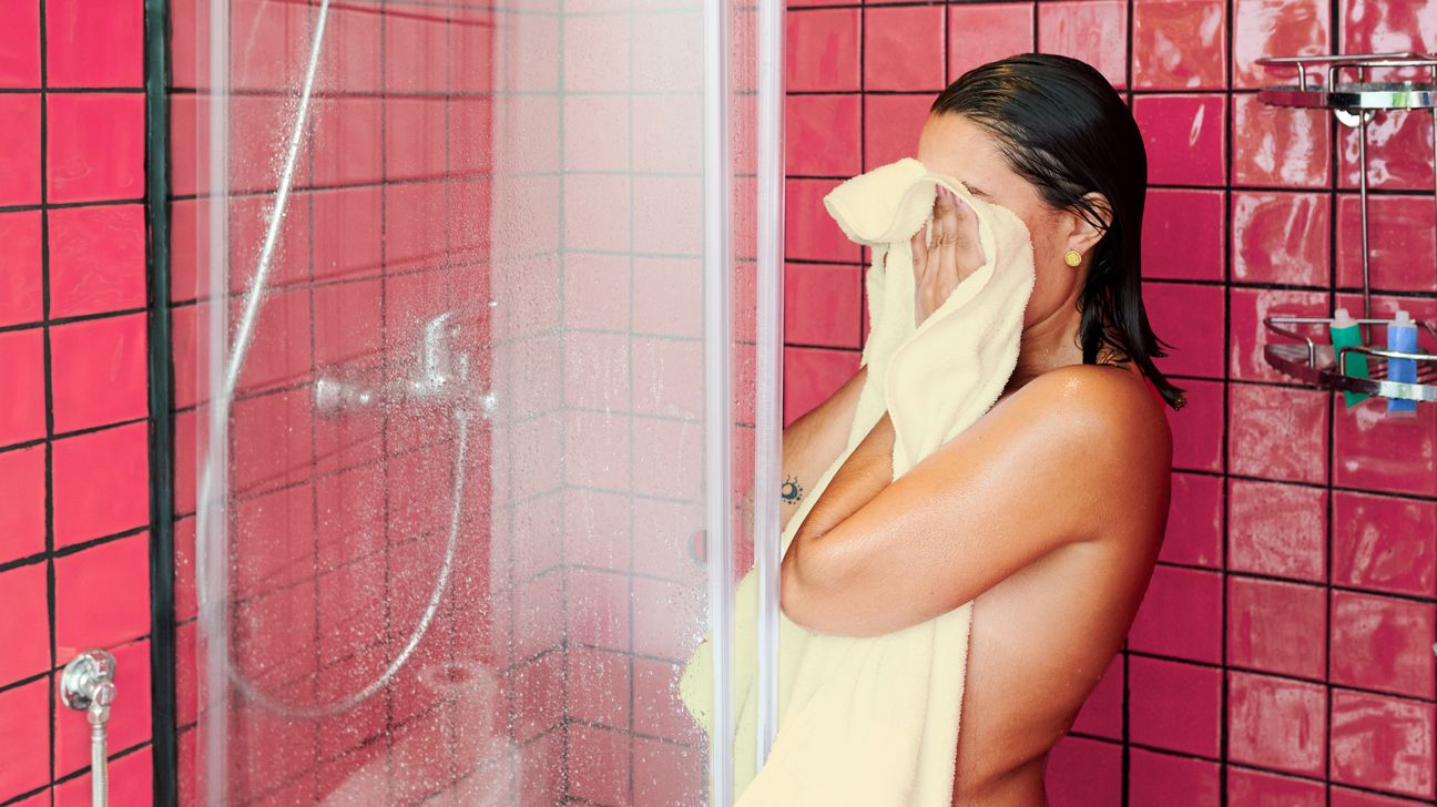 girl wiping her face in the shower
