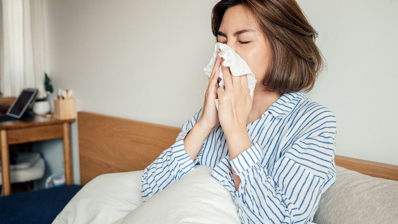 woman blowing her nose in bed