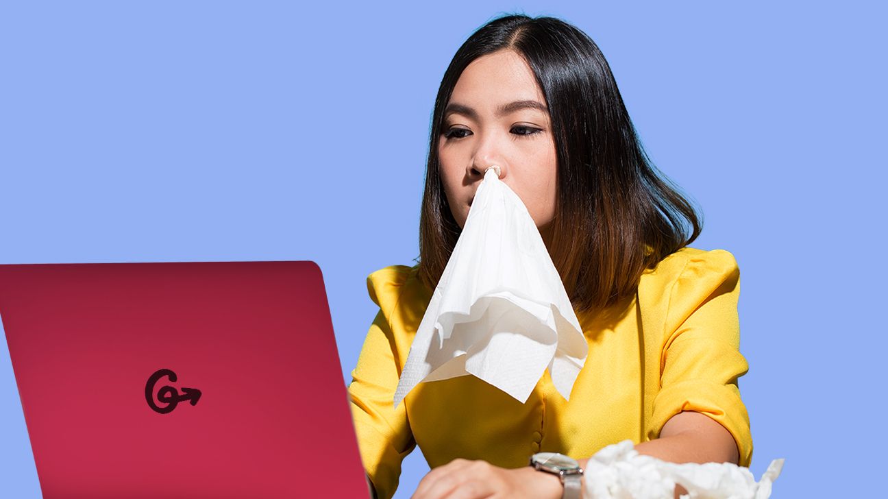 Girl with tissue in her nose, working on a computer