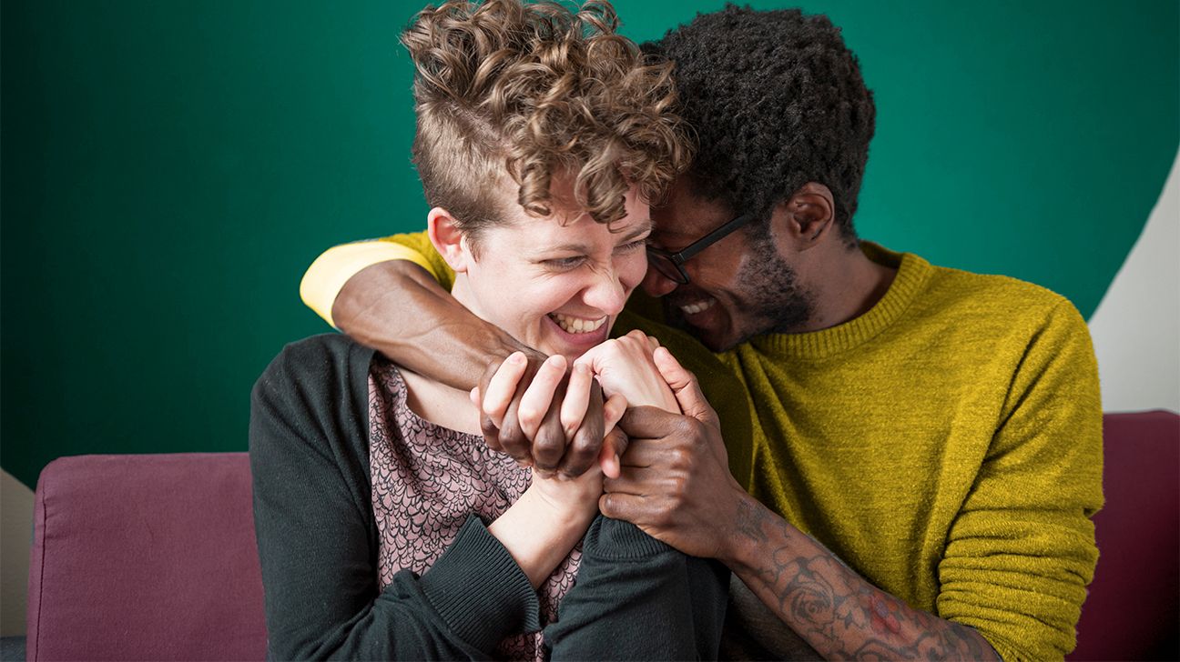 Couple with intertwined hands laughing playfully header crop