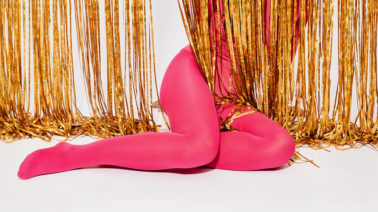 female legs in pink tights behind gold streamers