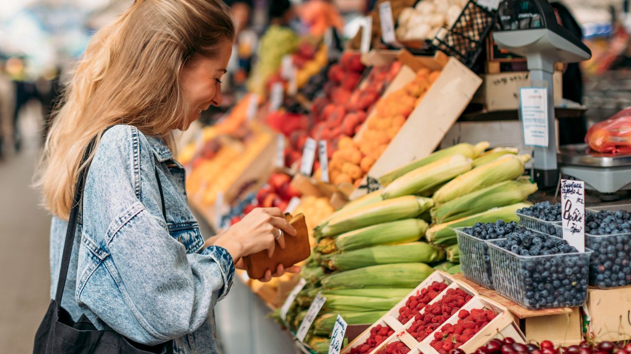 young woman buying fruits and vegetables at an outdoor market