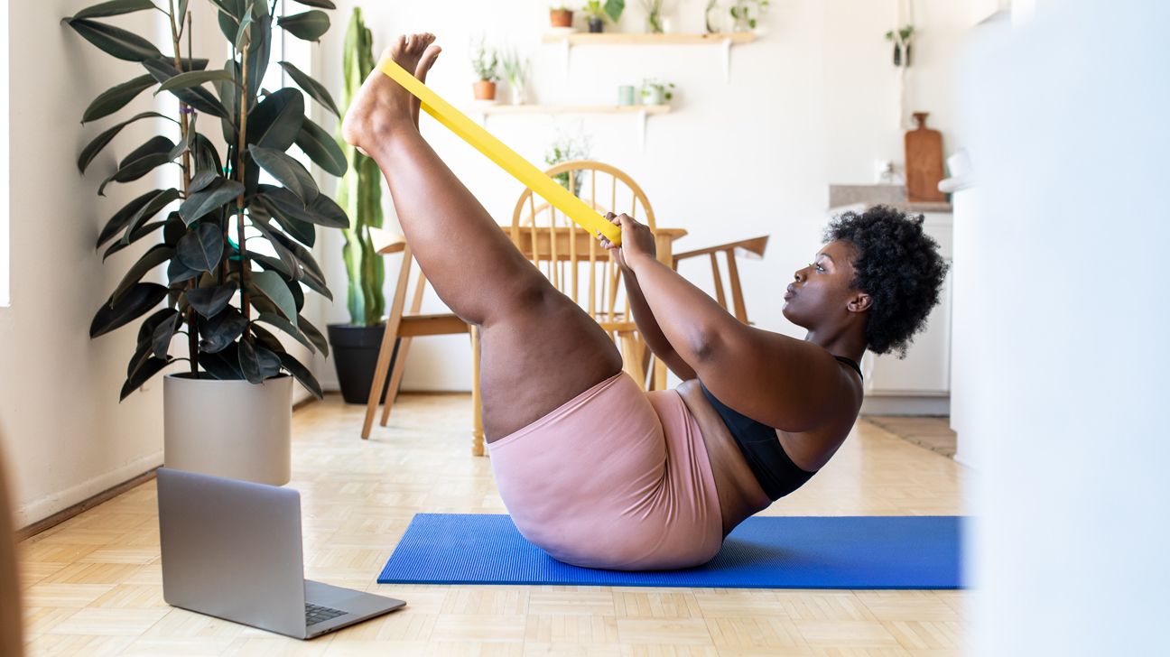 woman stretching with a fitness band on a mat