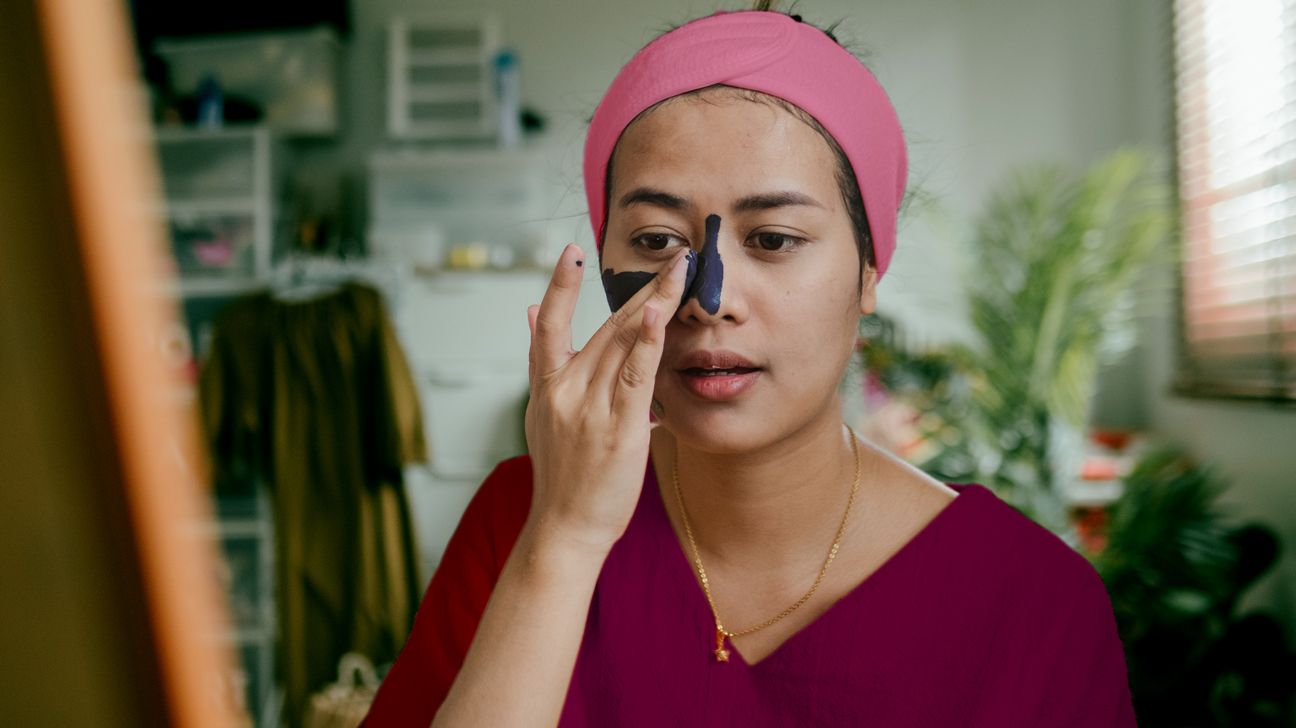 young woman applying charcoal mask