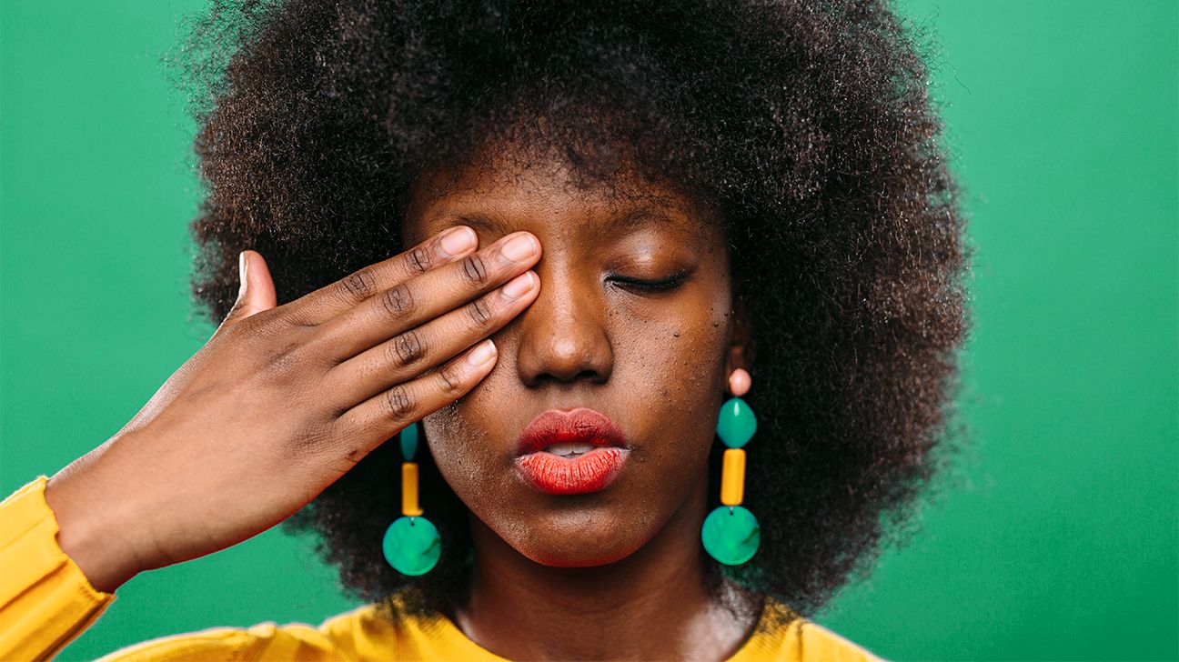 young woman covering one eye with her hand