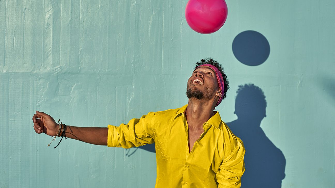 man playing with a ball in front of a blue wall