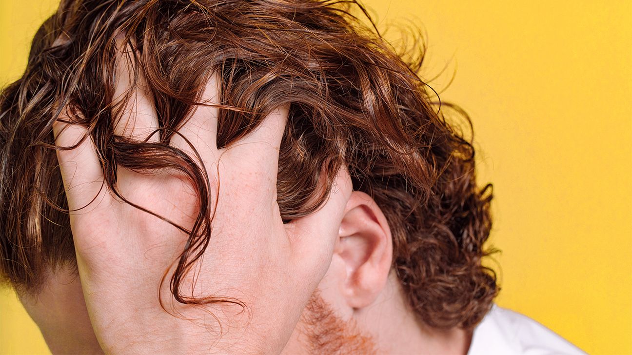 man with plaque psoriasis touches hair header