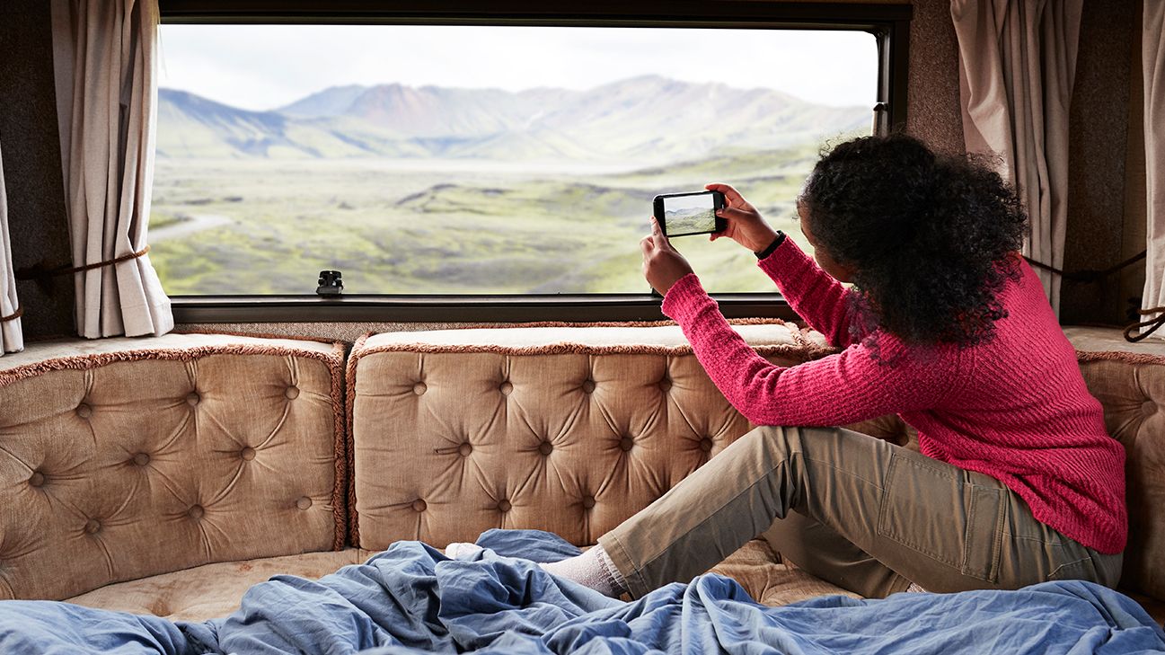 Female taking a photo of mountains in camper van