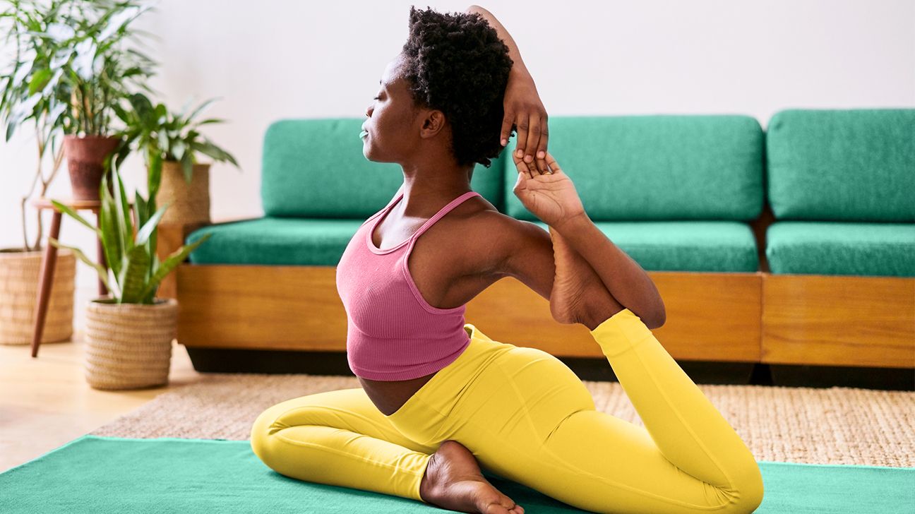 One legged king pigeon pose. African american lady stretching leg and  exercising on yoga mat, yellow background Stock Photo by ©Milkos 515352370