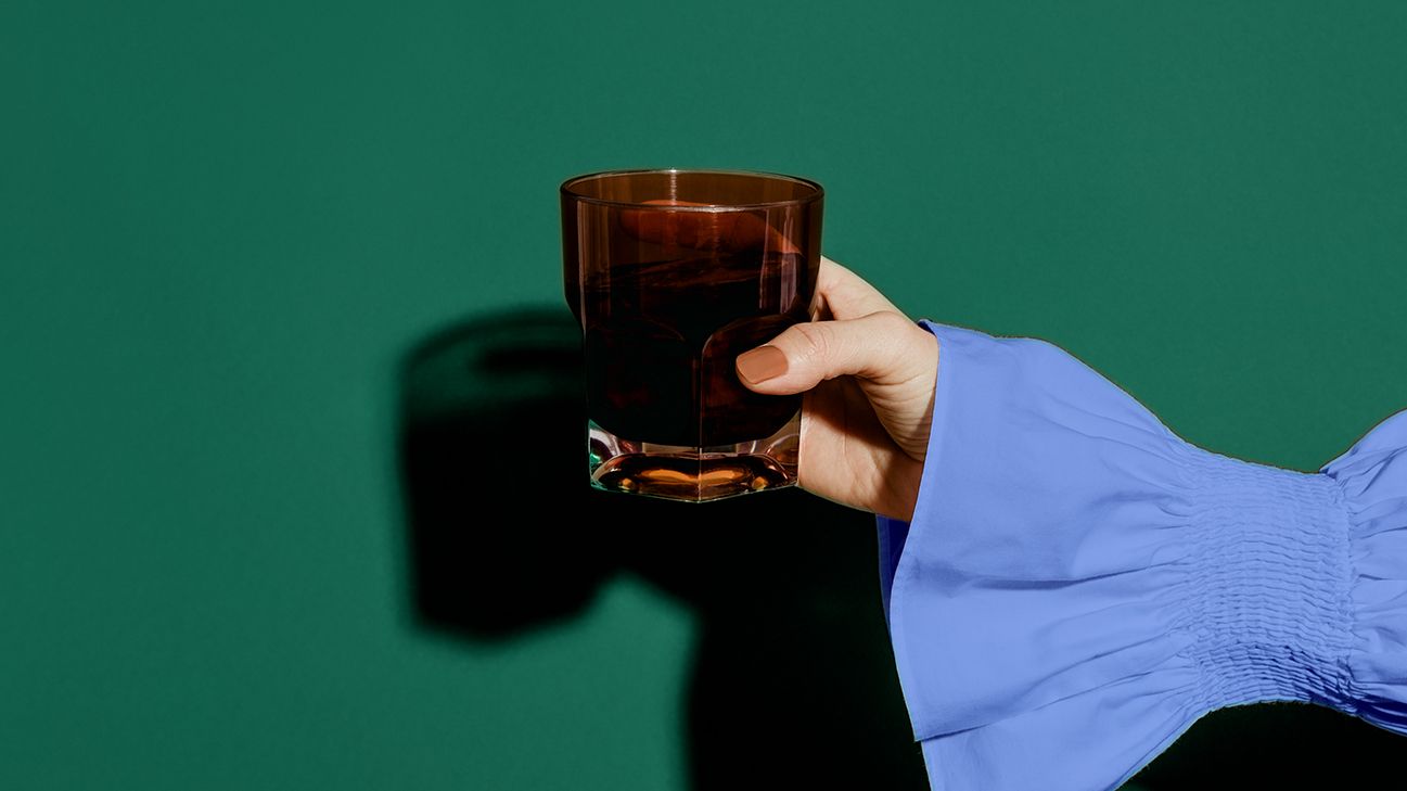 person holding glass of prune juice