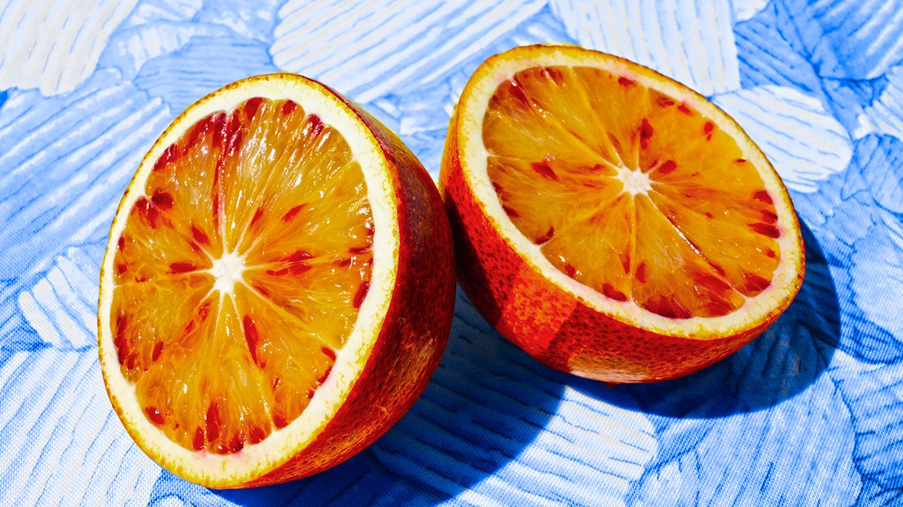 two halves of.a blood orange on blue background