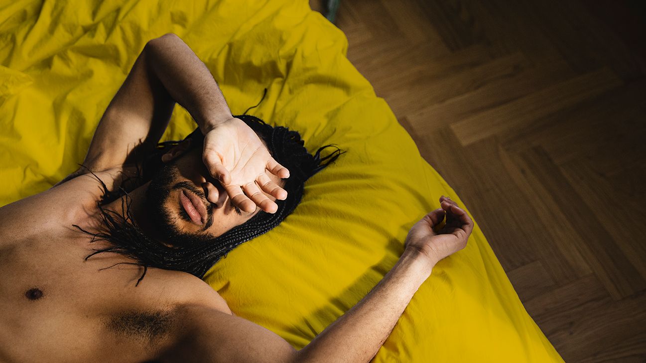 person lying on bed with hand over face
