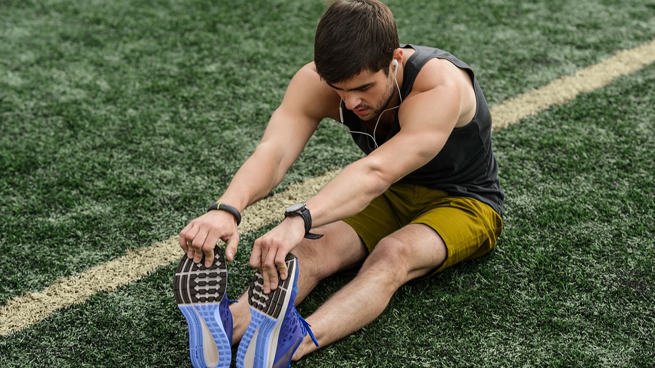 person stretching tight hamstrings on grass