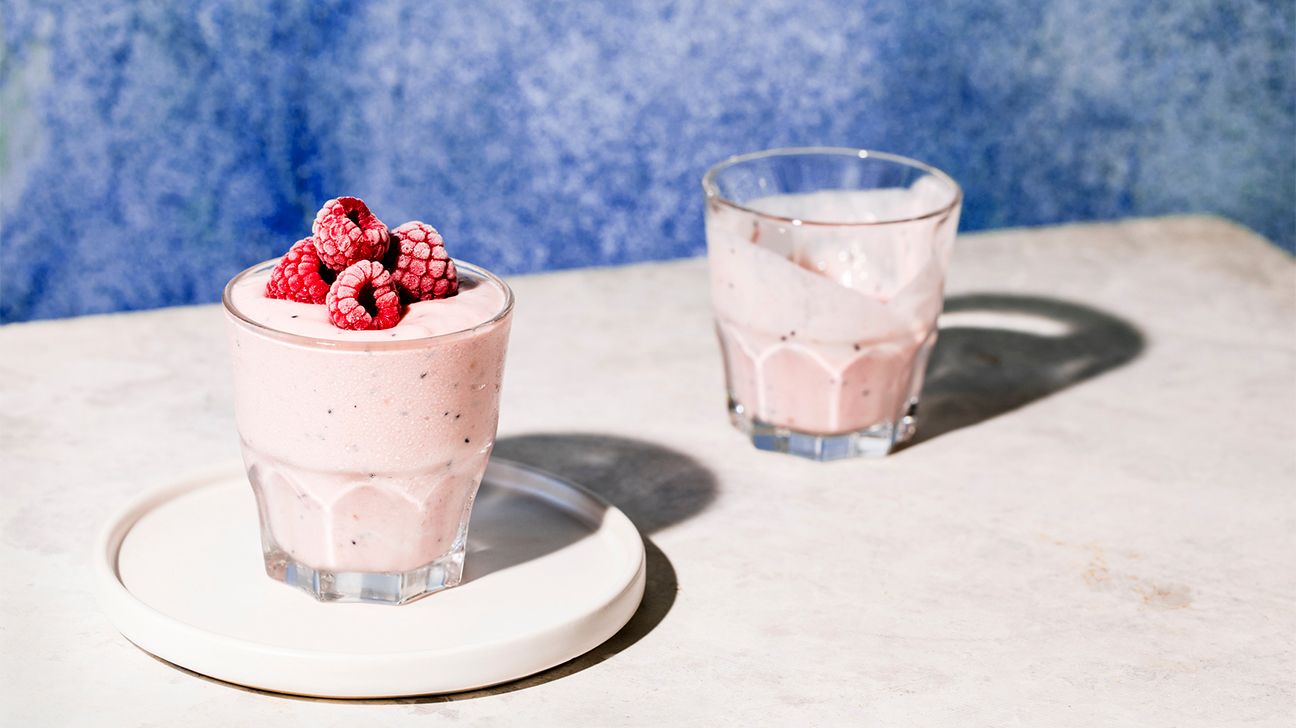pink smoothie in a glass with raspberries on top