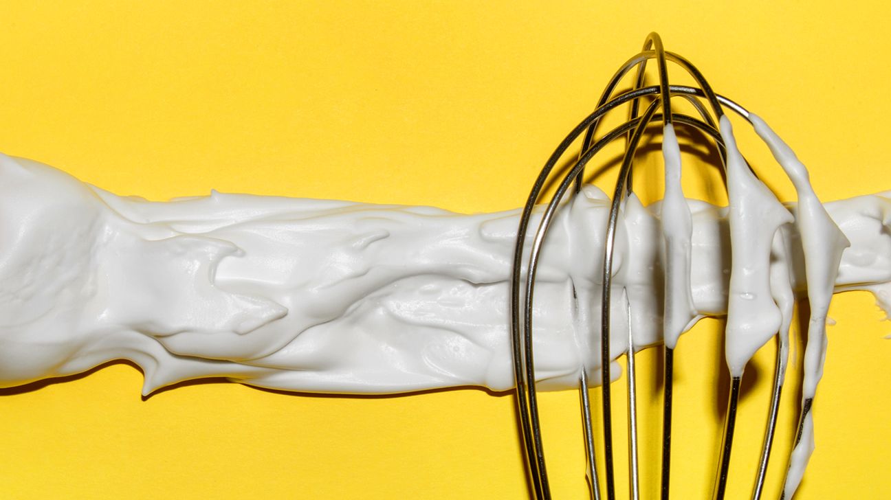 Meringue dessert on a whisk on yellow background