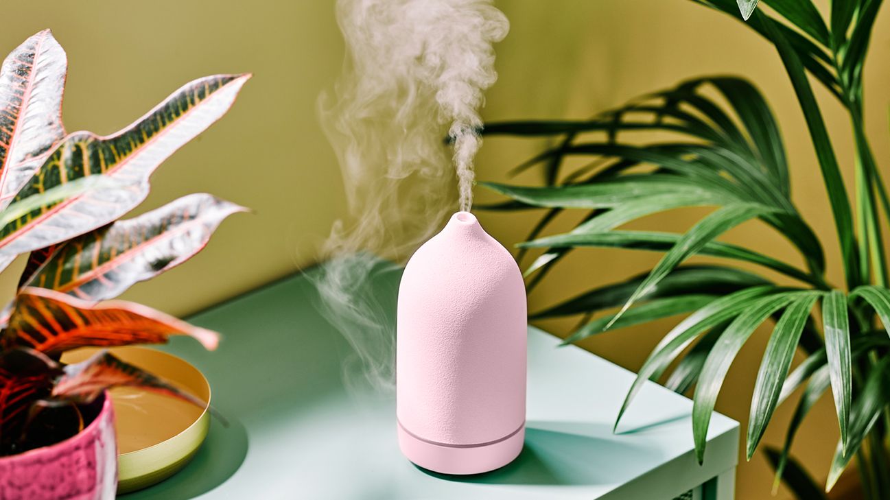 pink essential oil diffuser sits on green table