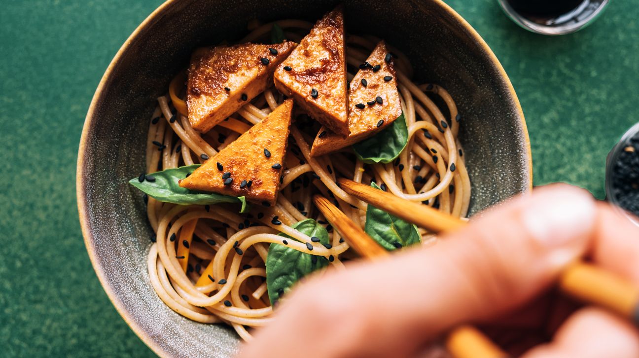 Bowl of Asian noodles with sprouted tofu and chopsticks