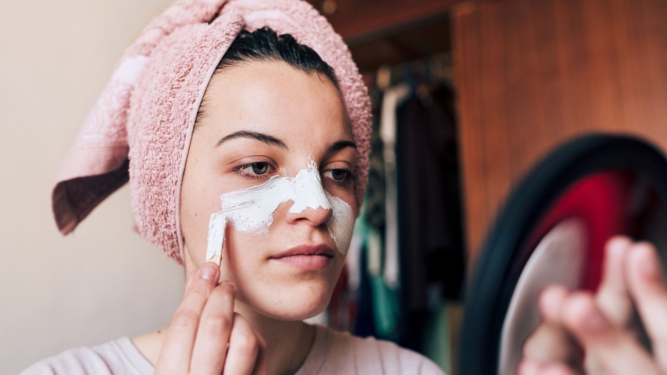 postpartum person putting acne cream on face