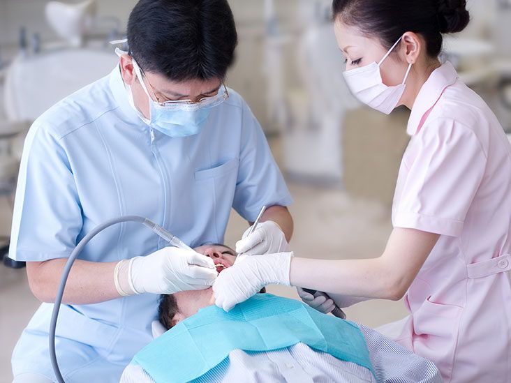 Dentist putting putty stone into patient mouth for dental