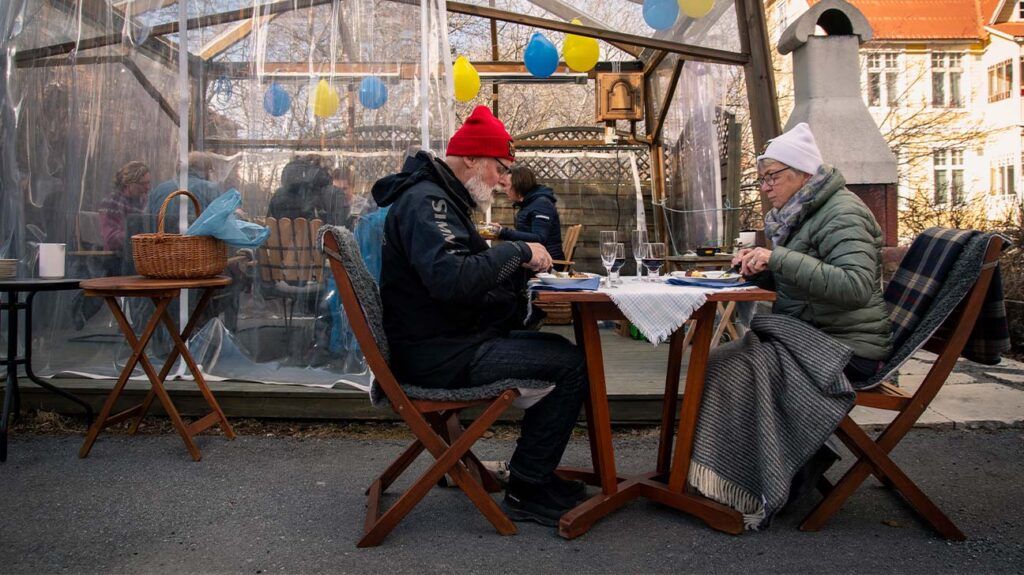 An older couple eat their dinner, keeping a distance from the rest of their family, on April 18, 2020, in Östersund, Sweden