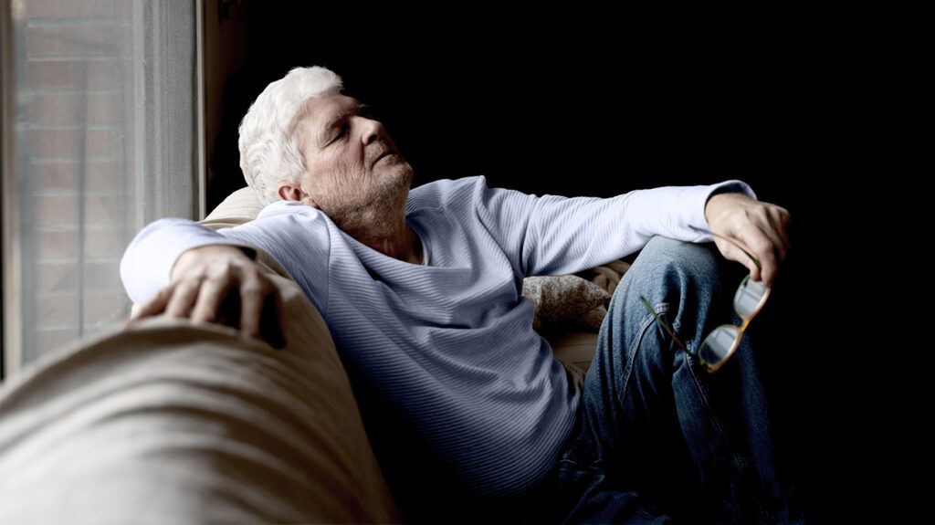 Un uomo anziano con l'Alzheimer che fa un pisolino su un divano.