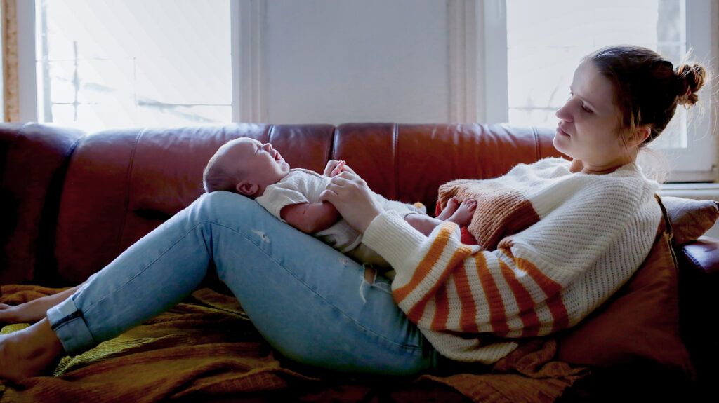 A woman lying on a couch with her baby.