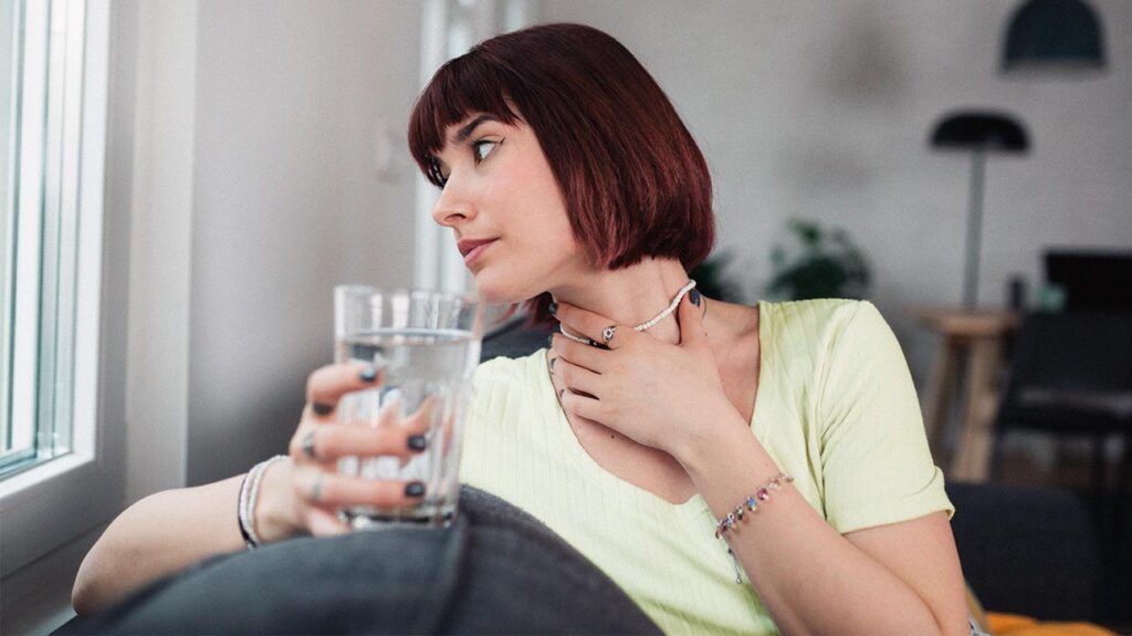 a young woman is drinking a glass of water