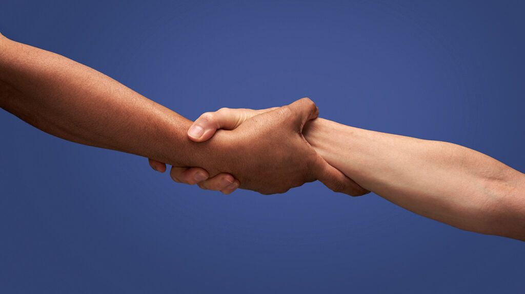 Two people clasping hands against a blue background -1.