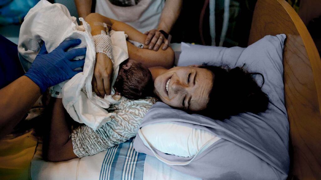 A parent holding their newborn baby after having general anesthesia during delivery -1.