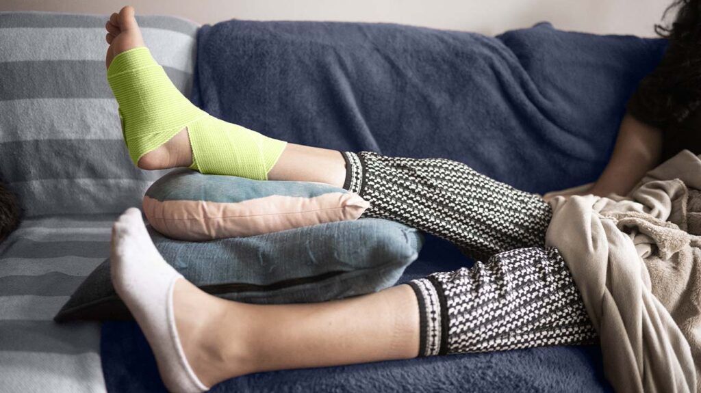 a person is lying on a sofa with a bandaged ankle