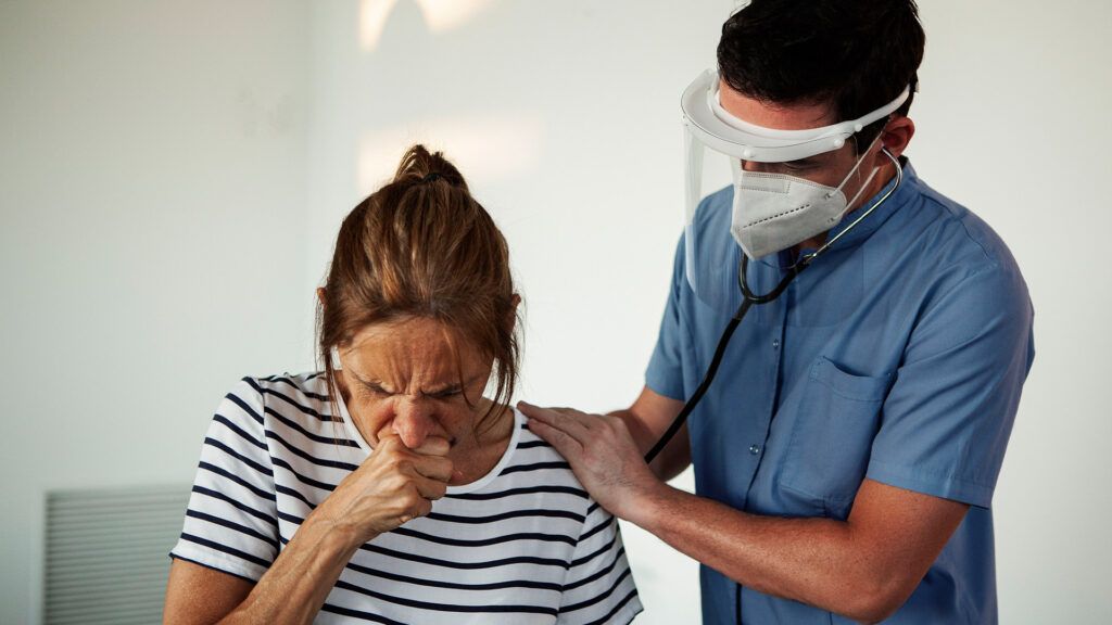 A doctor wearing a mask is soothing a person with TB coughing -1.