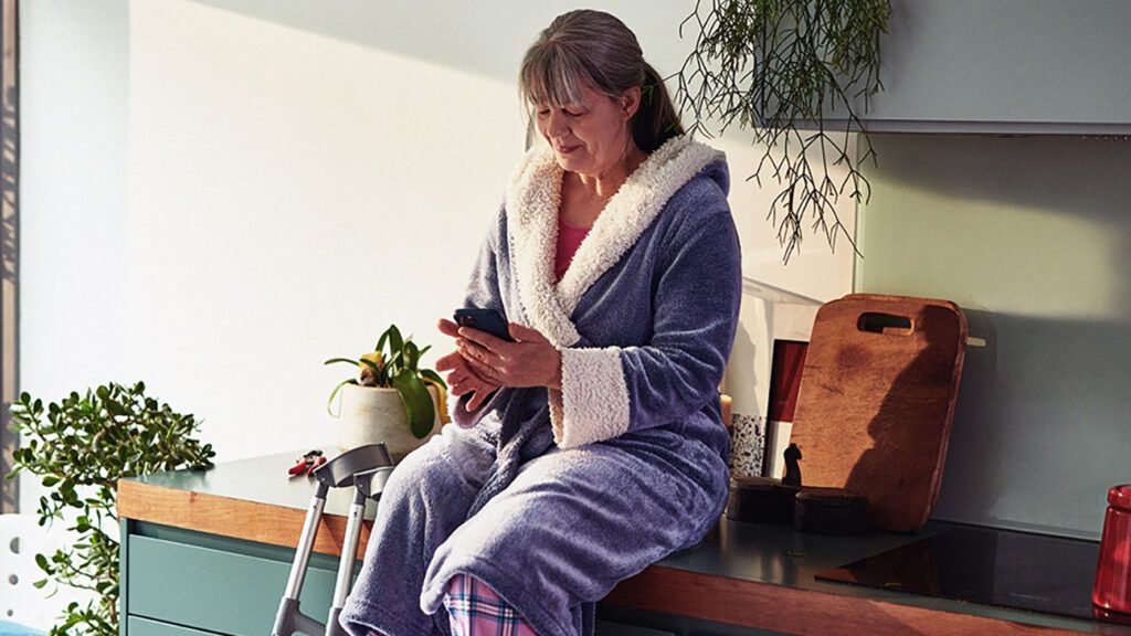 A person is sitting on a kitchen counter and looking at their phone.