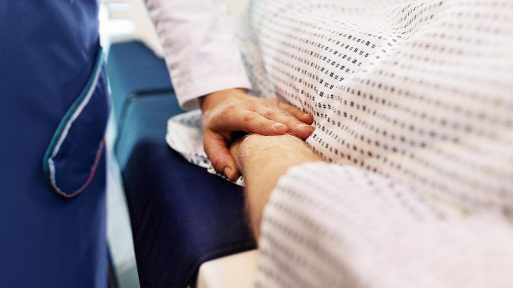 A person touching the hand of someone with advanced liver cancer.-2