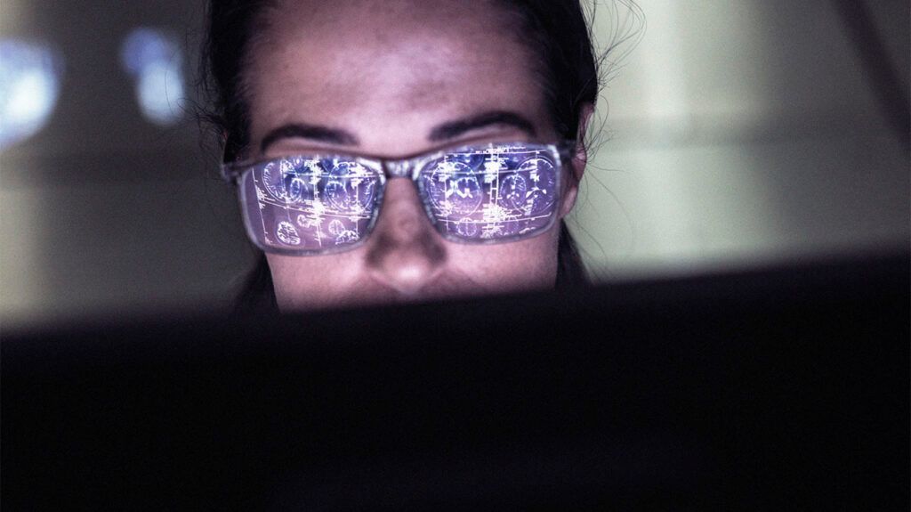 A person with a brain aneurysm reading something on a screen that's reflected in their glasses.-1