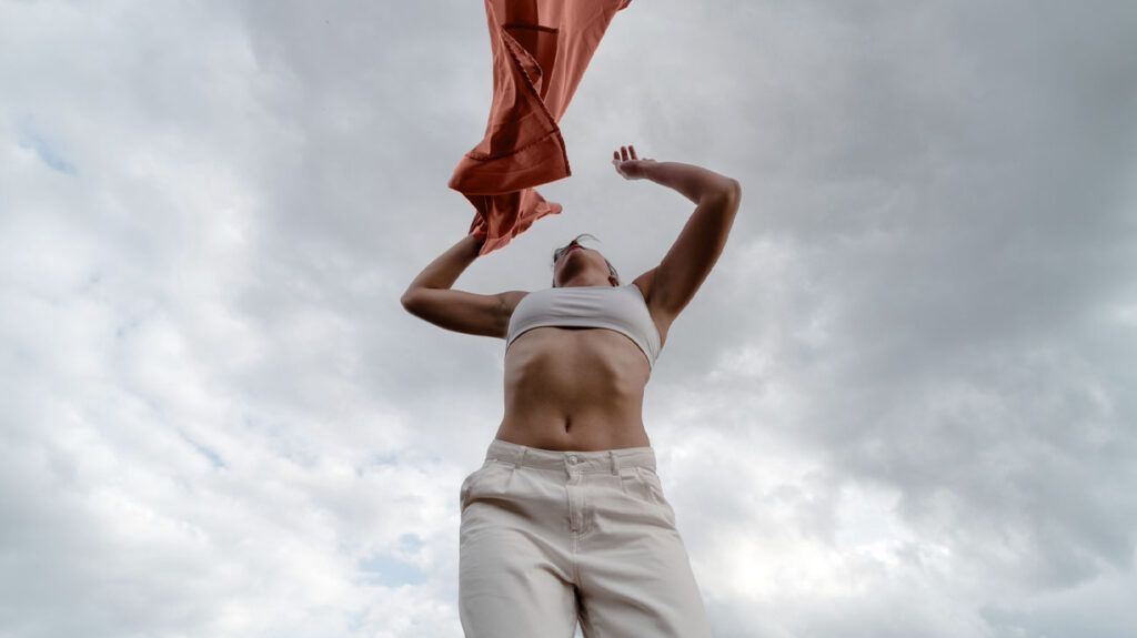 A woman with endometrial polyps looking up toward the sky and waving a scarf -1.