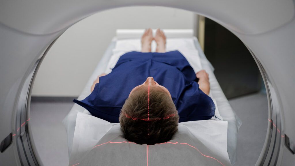 A woman in a blue hospital gown lying in an MRI machine.