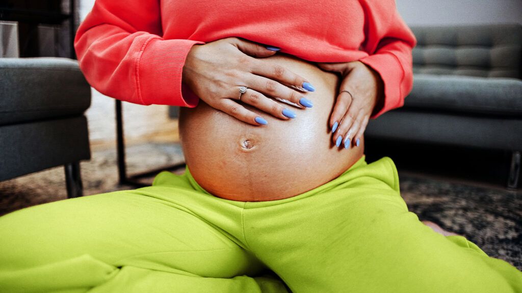 Close up of a pregnant person in a bright sweatsuit-1