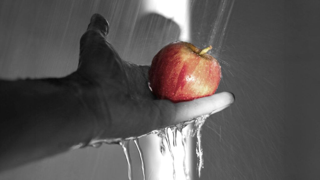 A person washing an apple in water to practice food safety -1.