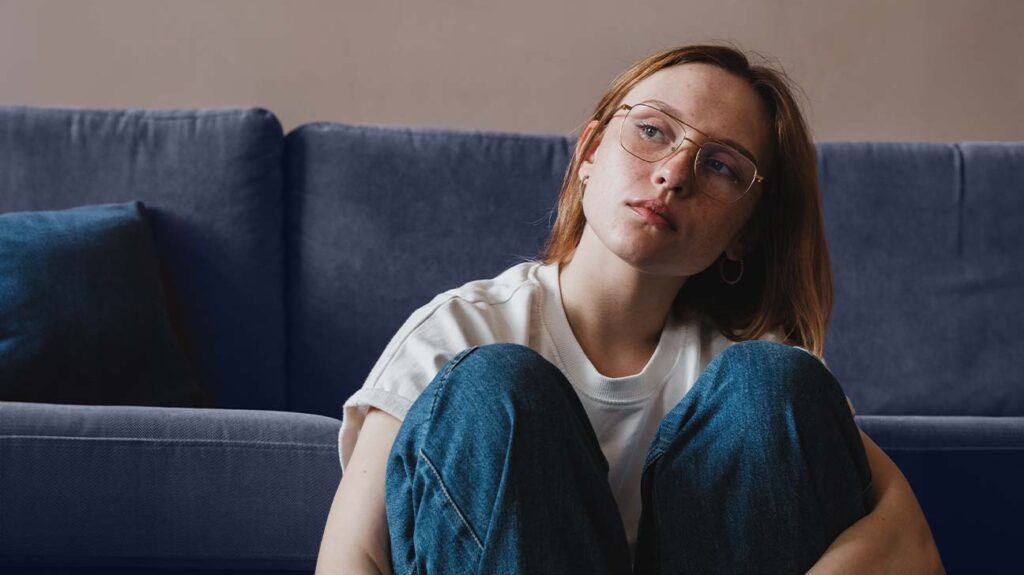 A woman sitting on the sofa experiencing stress which can affect endometriosis -1.
