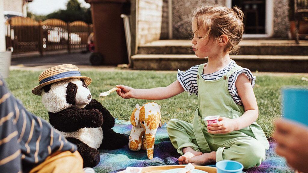 Children sit outside and have a Teddy Bear's Picnic