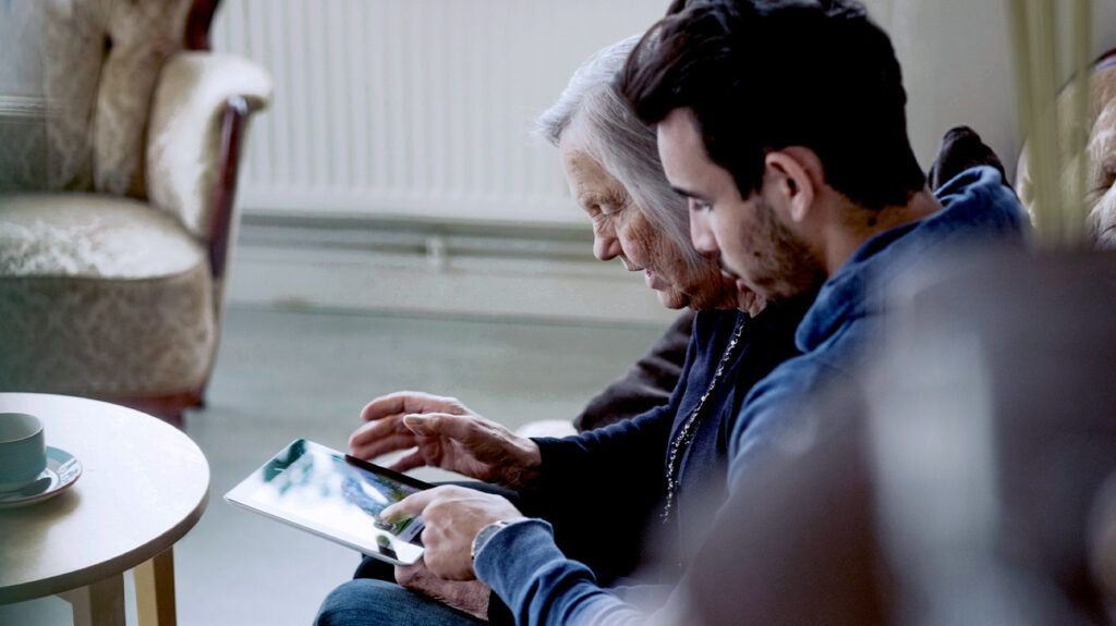 Caretaker and senior woman using digital tablet at nursing home